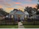 Charming cottage-style home with a metal roof, a picket fence, and a cozy front porch, set against a beautiful sunset backdrop at 632 Magnolia Dr., Georgetown, SC 29440
