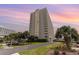 Exterior view of a high-rise building with balconies, surrounded by palm trees and landscaping at 9820 Queensway Blvd. # 301, Myrtle Beach, SC 29572