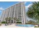 Exterior view of a high-rise building with balconies, surrounded by palm trees with a pool in the front at 9820 Queensway Blvd. # 301, Myrtle Beach, SC 29572