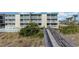 Low-rise condo complex featuring a pool, a boardwalk, and a beautifully landscaped front entrance at 105 S Ocean Blvd. # 108, North Myrtle Beach, SC 29582