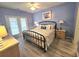 Comfortable bedroom with light blue walls, a black iron bed frame, and access to a balcony at 1058 Sea Mountain Hwy. # 14-203, North Myrtle Beach, SC 29582