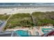 Aerial view of a beach with a pool area, green areas, and a walkway to the beach at 1401 S Ocean Blvd. S # 1003, North Myrtle Beach, SC 29582