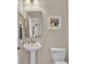 This bathroom features a pedestal sink, commode, framed mirror, and beach themed wall art at 1606 Lake Egret Dr., North Myrtle Beach, SC 29582