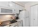 Close-up of the kitchen area with a white microwave, electric stove, and refrigerator at 4350 Intercoastal Dr. # 2207, Little River, SC 29566
