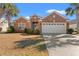 Charming brick home features a two-car garage, manicured bushes, and well-maintained lawn and mature palm trees at 4517 Planters Row Way, Myrtle Beach, SC 29579