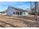 View of the backyard showcasing a covered patio, grassy expanse, and mature trees at 5501 Bristle Cone Ct., Myrtle Beach, SC 29577
