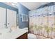 Bright bathroom with blue walls, beach themed shower curtain, and wooden vanity at 556 Cedar Lakes Dr., Little River, SC 29566