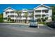 Attractive condo building with multiple balconies and mature landscaping near parking lot at 5801 Oyster Catcher Dr. # 723, North Myrtle Beach, SC 29582