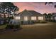 Backyard view of a brick home featuring a screened porch and manicured landscaping at dusk at 598 Summer Green Ct., Sunset Beach, NC 28468