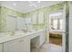 Bright bathroom with dual sinks, white cabinets, framed mirrors, and tropical wallpaper leading to the Primary bedroom at 63 Mckissick Dr. # 2B, Pawleys Island, SC 29585