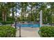 Community outdoor pool with seating and umbrellas, surrounded by tall pine trees at 699 Riverwalk Dr. # 202, Myrtle Beach, SC 29579
