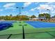 Brightly lit tennis court with blue and green surfaces and black fences with glimpses of surrounding trees at 7079 Shooting Star Way, Myrtle Beach, SC 29579
