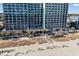 High-rise oceanfront building with a sandy beach and blue umbrellas providing shade at 2311 S Ocean Blvd. # 771, Myrtle Beach, SC 29577
