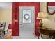 Inviting entryway with decorative door, side table with lamp, and bright red accent wall at 3079 Alice Ln., Little River, SC 29566