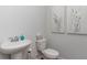 Simple powder room with a white pedestal sink, toilet, and decorative artwork enhancing the clean design at 6007 Forest Dell Ct, Myrtle Beach, SC 29579