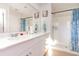 Well-lit bathroom with a double sink vanity, large mirror, and a walk-in shower with blue curtain at 723 Joywood Dr., Longs, SC 29568