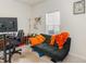 Comfortable living room with a dark futon, bright orange pillows and blanket, and natural light from the window at 723 Joywood Dr., Longs, SC 29568