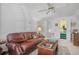 Living room featuring a leather couch, ceiling fan, and access to a room with green carpet at 75 Haig Ct., Georgetown, SC 29440