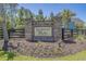 Community sign for Longwood Bluffs with flower beds, landscaping, and a partial view of a house at 9035 Binnicker Dr., Murrells Inlet, SC 29576