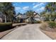 Charming brick home with a circular driveway, lush landscaping, and mature palm trees at 9800 Plumfield Ct., Myrtle Beach, SC 29579
