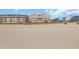Beachfront view of the condo complex with a sandy beach and blue sky at 1113 N Ocean Blvd. # 101, Surfside Beach, SC 29575