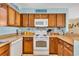 Kitchen with wooden cabinets, white appliances, and a light blue backsplash at 1113 N Ocean Blvd. # 101, Surfside Beach, SC 29575