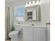 Bathroom with a white vanity, toilet, a window that lets in natural light, and a bathtub with a shower at 2000 N Waccamaw Dr., Garden City Beach, SC 29576