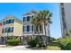 Charming two-story beach house on stilts with palm trees and a well-maintained lawn at 2000 N Waccamaw Dr., Garden City Beach, SC 29576