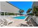 Inviting backyard pool surrounded by lounge chairs, with palm trees and a privacy fence at 2000 N Waccamaw Dr., Garden City Beach, SC 29576