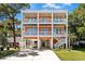 Stunning three-story beach house with white railings, covered parking, and an inviting stairway on a sunny day at 3304 Palm St., North Myrtle Beach, SC 29582
