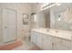 Bright bathroom with white cabinets, a large mirror, and floral wallpaper, offering a clean, functional space at 3986 Lochview Dr., Myrtle Beach, SC 29588