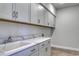 Bright laundry room features gray cabinets, quartz countertop, chrome hardware, and wood-look laminate flooring at 4036 Bucolic Loop, Myrtle Beach, SC 29588