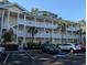 Bright, yellow condo building with multiple balconies, white railings, and palm trees offers a coastal living vibe at 4221 Hibiscus Dr. # 101, Little River, SC 29566