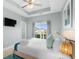 Bright main bedroom featuring a king bed, tray ceiling, and a window with a view of the neighborhood at 436 E Third St., Ocean Isle Beach, NC 28469