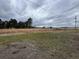 View of the backyard featuring overgrown grass, scattered debris, and an expanse of open space under cloudy skies at 657 Mulberry Rd., Salters, SC 29590