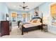 Light blue bedroom features a black four-poster bed, ceiling fan, and two large windows with white trim at 9100 Sw Fountain St., Calabash, NC 28467