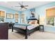 Light blue bedroom features a black four-poster bed, ceiling fan, and two large windows with white trim at 9100 Sw Fountain St., Calabash, NC 28467