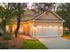 Beige home with white garage door, side patio with string lights, and manicured lawn at 9100 Sw Fountain St., Calabash, NC 28467