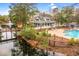 Community pool area with a bridge over a lagoon, surrounded by lush trees at 9100 Sw Fountain St., Calabash, NC 28467