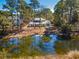 Backyard featuring pond with green algae and home tucked behind mature trees at 144 Springfield Rd., Pawleys Island, SC 29585