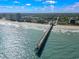 Stunning aerial view of the pier stretching into the ocean, showcasing the coastline and vibrant city skyline at 201 S Ocean Blvd. # 217, Myrtle Beach, SC 29577
