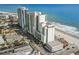 An elevated view of the condo and oceanfront, highlighting building architecture, palm trees, and beach access at 201 S Ocean Blvd. # 217, Myrtle Beach, SC 29577