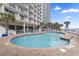 Inviting outdoor pool with surrounding lounge chairs and palm trees at an oceanfront resort on a sunny day at 201 S Ocean Blvd. # 217, Myrtle Beach, SC 29577