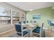 Bright dining room with a modern table set for six, complemented by blue chairs and ample natural light at 310 5Th Ave. N # 206, Surfside Beach, SC 29575