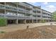 View of building featuring multiple stories, open-air garages, and outdoor area with gravel at 310 5Th Ave. N # 206, Surfside Beach, SC 29575
