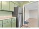 Kitchen with stainless steel refrigerator, green cabinets and view to another room at 310 5Th Ave. N # 206, Surfside Beach, SC 29575