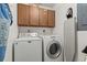 Well-lit laundry room with a washer, a dryer, an ironing board, and wood cabinets at 310 5Th Ave. N # 206, Surfside Beach, SC 29575