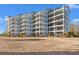 Condo building with multiple floors and balconies overlooks a well-maintained lawn with palm trees at 4440 Nassau Ct. # D-507, Little River, SC 29566