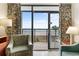 Cozy living room featuring comfortable armchairs, a lamp, and an ocean view through sliding glass doors to the balcony at 4800 S Ocean Blvd. # 204, North Myrtle Beach, SC 29582