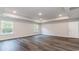 A spacious bedroom featuring wood-look flooring, tray ceiling, and abundant natural light from two windows at 515 Haven View Way, Murrells Inlet, SC 29576